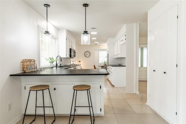 kitchen featuring a breakfast bar area, kitchen peninsula, sink, and white cabinets