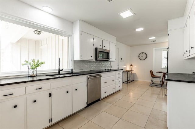 kitchen with white cabinetry, sink, stainless steel appliances, decorative backsplash, and light tile patterned floors