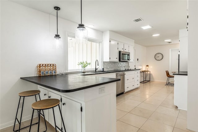 kitchen with white cabinetry, sink, backsplash, kitchen peninsula, and appliances with stainless steel finishes