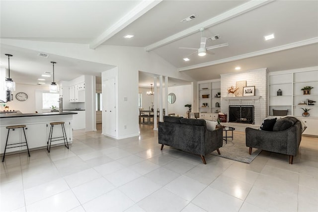 living room featuring built in shelves, a fireplace, lofted ceiling with beams, and ceiling fan with notable chandelier