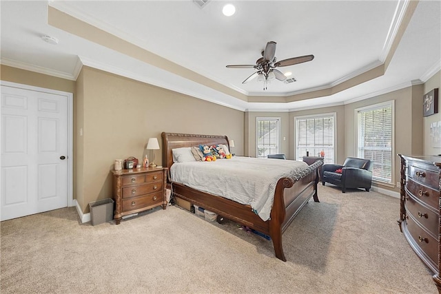 bedroom featuring ceiling fan, ornamental molding, light carpet, and a tray ceiling