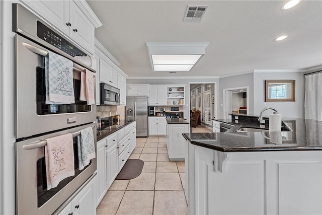 kitchen with white cabinetry, sink, appliances with stainless steel finishes, and an island with sink