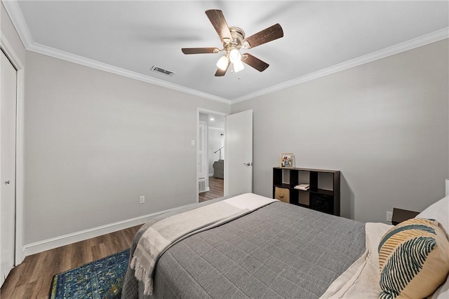 bedroom featuring visible vents, baseboards, ornamental molding, wood finished floors, and a ceiling fan