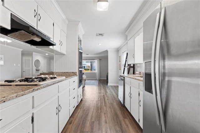 kitchen with ornamental molding, under cabinet range hood, stainless steel fridge, white cabinets, and white gas stovetop