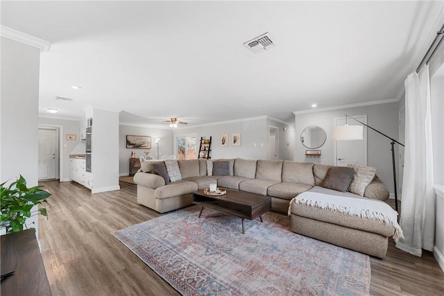 living room featuring visible vents, light wood-style flooring, crown molding, and baseboards