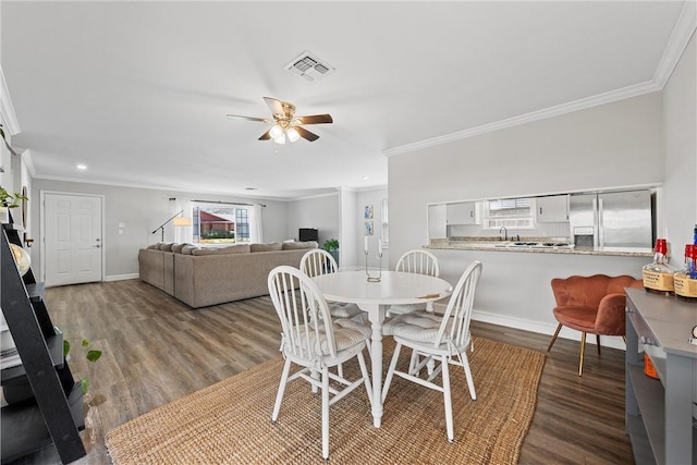 dining room with crown molding, wood finished floors, visible vents, and baseboards