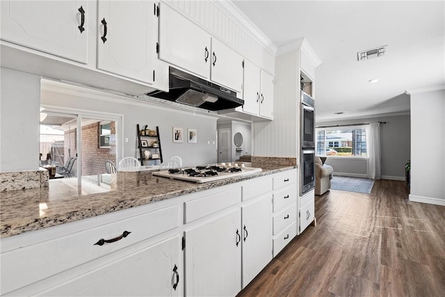 kitchen with visible vents, ornamental molding, under cabinet range hood, white cabinetry, and dark wood-style flooring