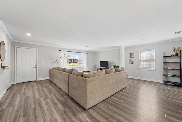 living area featuring baseboards, plenty of natural light, wood finished floors, and ornamental molding