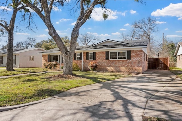 ranch-style home featuring a front yard, brick siding, driveway, and fence