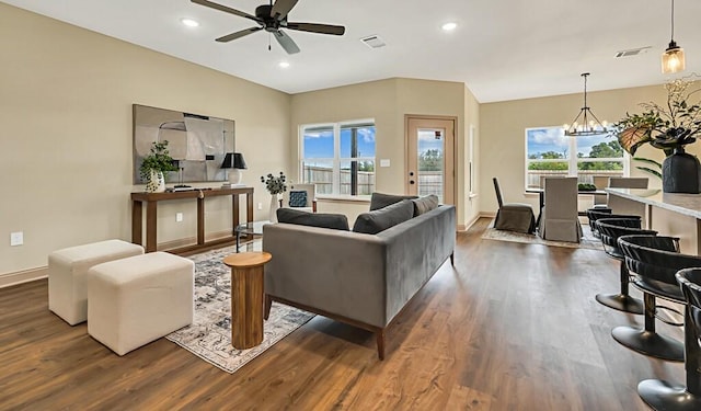 living room with dark hardwood / wood-style flooring, plenty of natural light, and ceiling fan with notable chandelier