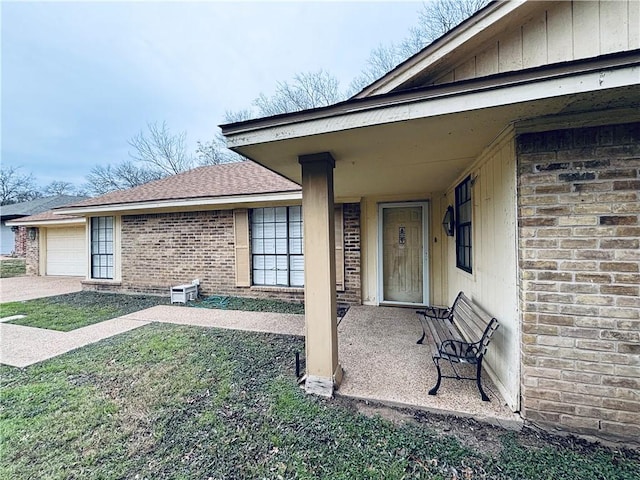 view of exterior entry featuring a garage and a yard