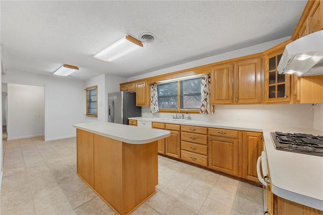 kitchen featuring stainless steel fridge, a textured ceiling, exhaust hood, and sink