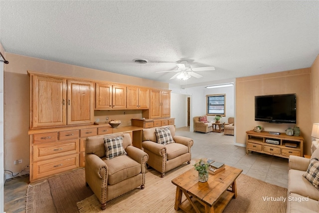 living room with ceiling fan and a textured ceiling