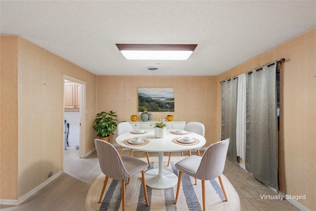 dining room featuring a textured ceiling and light wood-type flooring