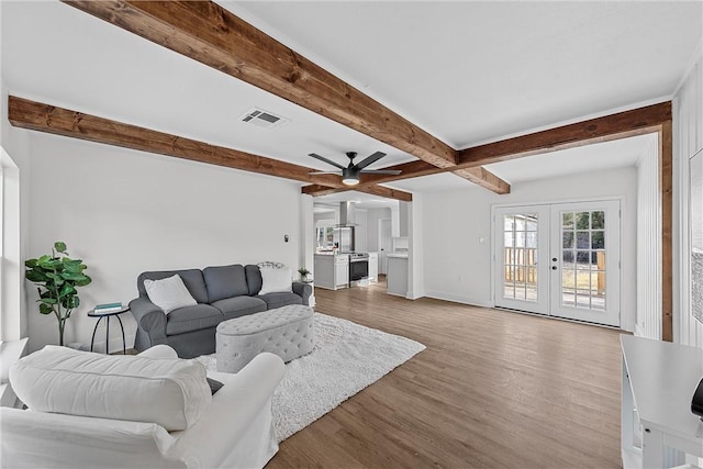 living room with ceiling fan, beam ceiling, light hardwood / wood-style flooring, and french doors