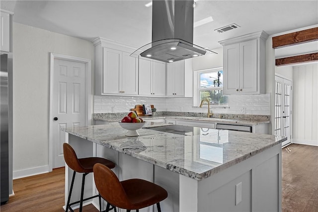 kitchen featuring island range hood, white cabinetry, hardwood / wood-style flooring, and a kitchen island