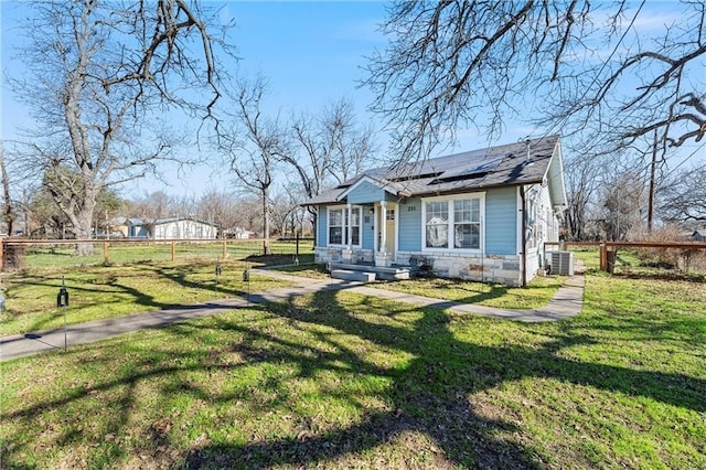 view of front of property with solar panels, cooling unit, and a front yard