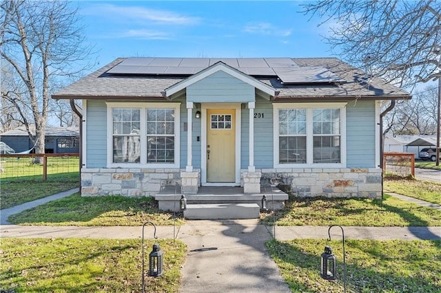 bungalow-style home with solar panels and a front lawn