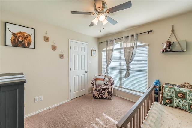 carpeted bedroom featuring a crib and ceiling fan