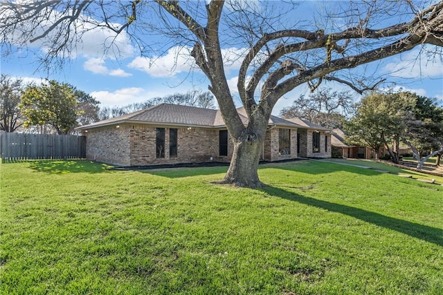 view of front facade with brick siding, a front yard, and fence