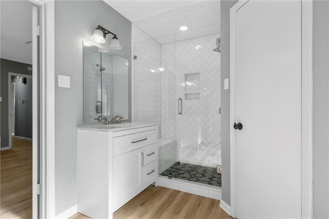 bathroom featuring a stall shower, baseboards, wood finished floors, and vanity