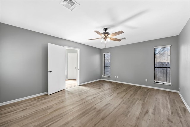 spare room with ceiling fan, wood finished floors, visible vents, and baseboards