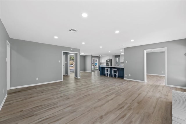 unfurnished living room with light wood-style flooring, recessed lighting, visible vents, and baseboards