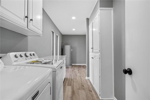 laundry area featuring water heater, cabinet space, light wood-style floors, separate washer and dryer, and baseboards