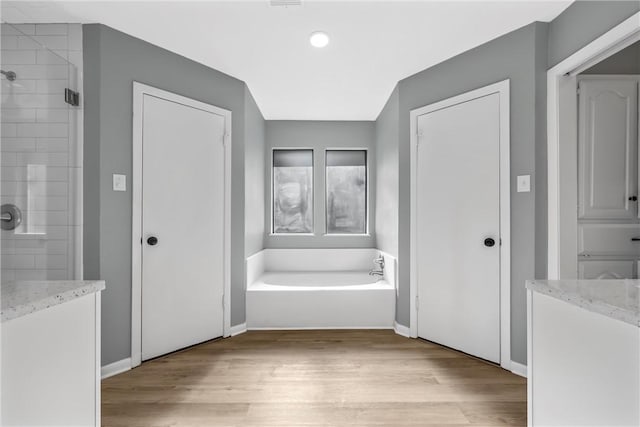 full bathroom featuring a tile shower, baseboards, a garden tub, and wood finished floors