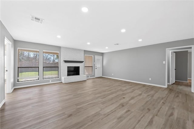 unfurnished living room with visible vents, baseboards, recessed lighting, a fireplace, and light wood-style floors