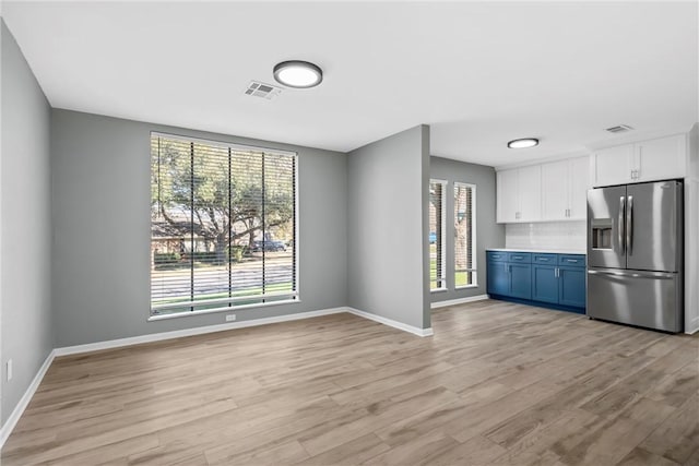 unfurnished dining area featuring visible vents, baseboards, and light wood-style flooring