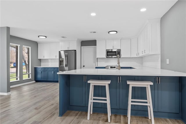 kitchen with stainless steel appliances, backsplash, a peninsula, and light countertops