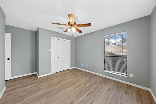 unfurnished bedroom featuring light wood-style flooring, baseboards, visible vents, and a closet