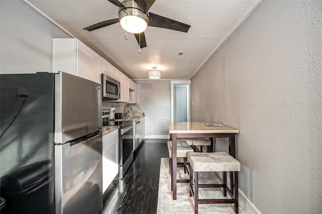 kitchen featuring sink, light stone counters, dark hardwood / wood-style floors, stainless steel appliances, and white cabinets