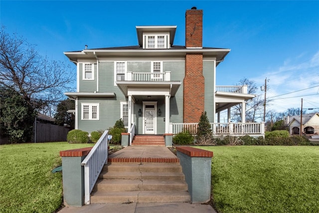 view of front facade with a balcony, covered porch, and a front lawn