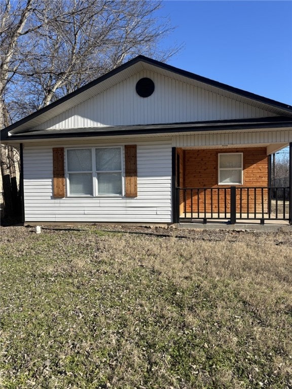 view of property exterior featuring a porch and a lawn