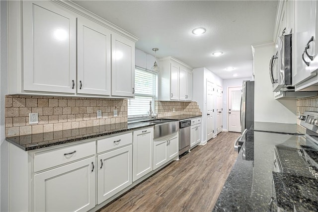 kitchen with white cabinets, decorative light fixtures, stainless steel appliances, and hardwood / wood-style floors