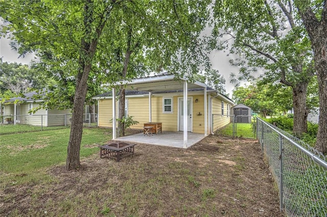 back of house with a lawn, a patio area, and an outdoor fire pit