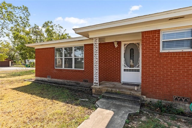 view of exterior entry featuring a yard