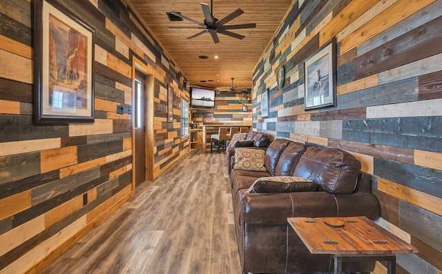 living room featuring hardwood / wood-style flooring, wooden walls, wooden ceiling, and ceiling fan