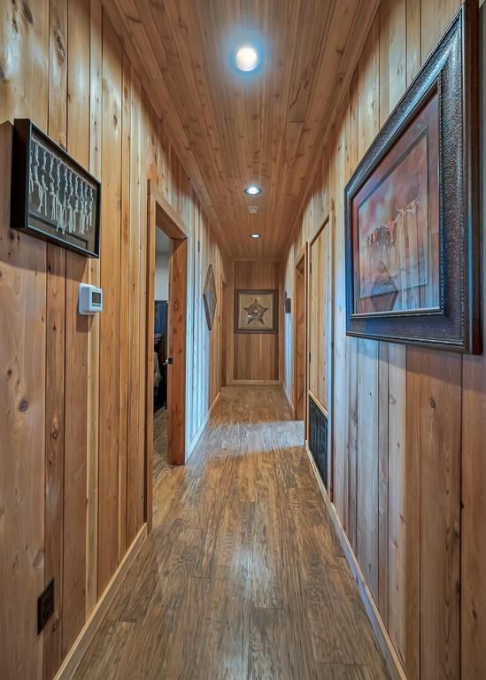 corridor with wood ceiling, wood-type flooring, and wooden walls