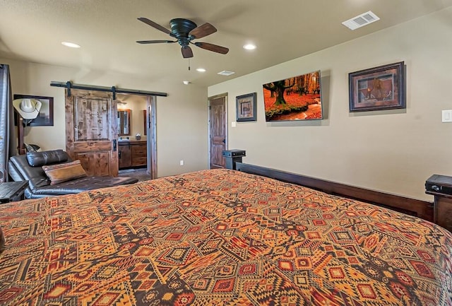 bedroom featuring ceiling fan, a barn door, and ensuite bath