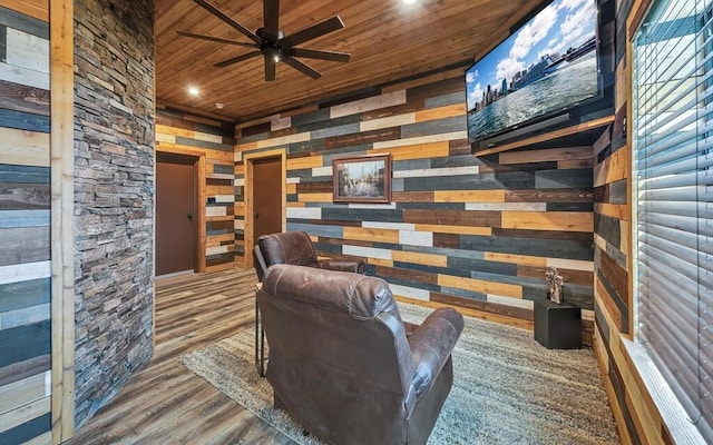 sitting room with wood ceiling, ceiling fan, hardwood / wood-style flooring, and wood walls