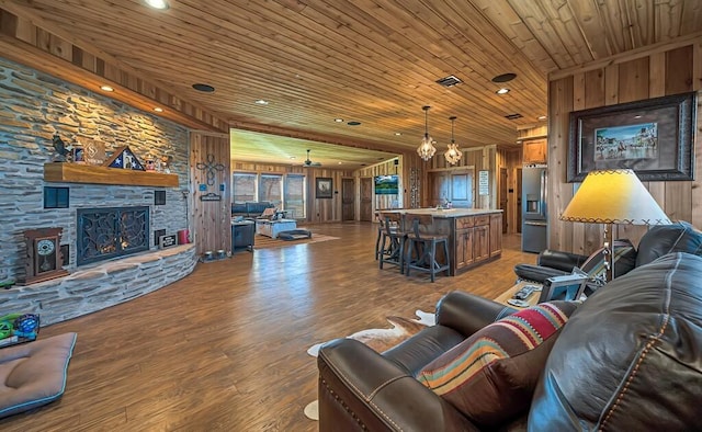 living room featuring hardwood / wood-style floors, wood ceiling, a fireplace, and wooden walls