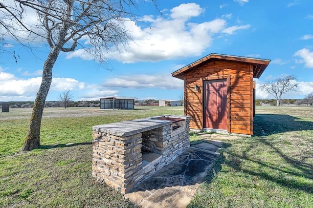 view of outdoor structure featuring a rural view and a lawn