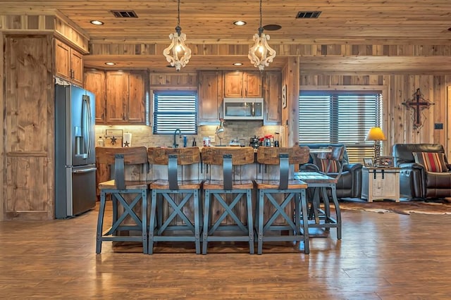 kitchen featuring a breakfast bar, wooden ceiling, dark hardwood / wood-style floors, pendant lighting, and stainless steel appliances