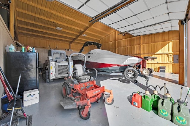 garage with black refrigerator and wooden walls