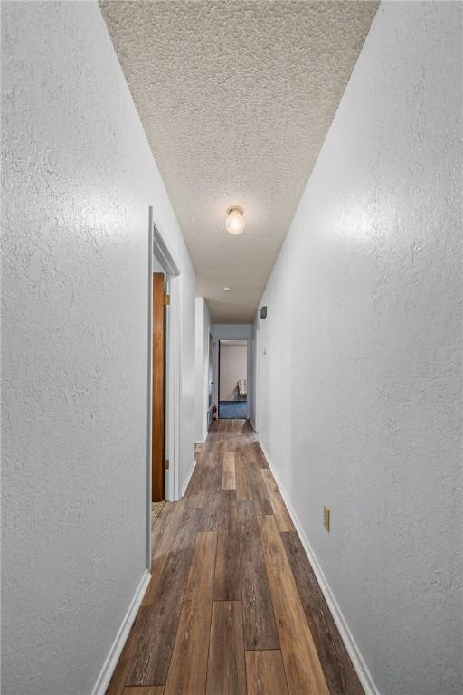 corridor featuring a textured ceiling and dark hardwood / wood-style floors