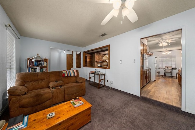 living room featuring a textured ceiling, dark hardwood / wood-style floors, and ceiling fan