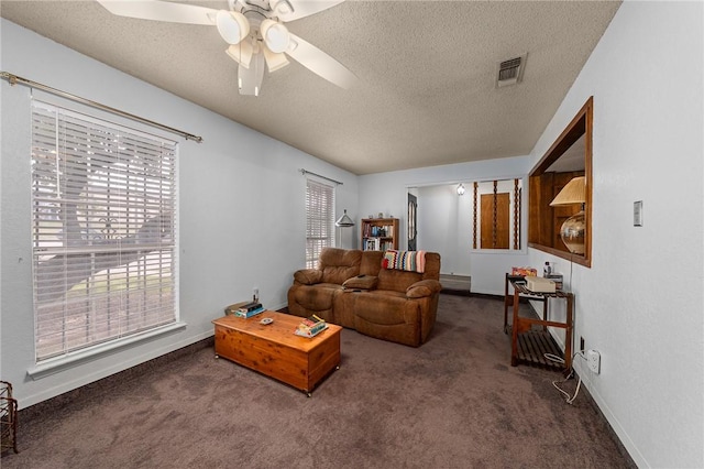 living room featuring dark colored carpet, a textured ceiling, and ceiling fan